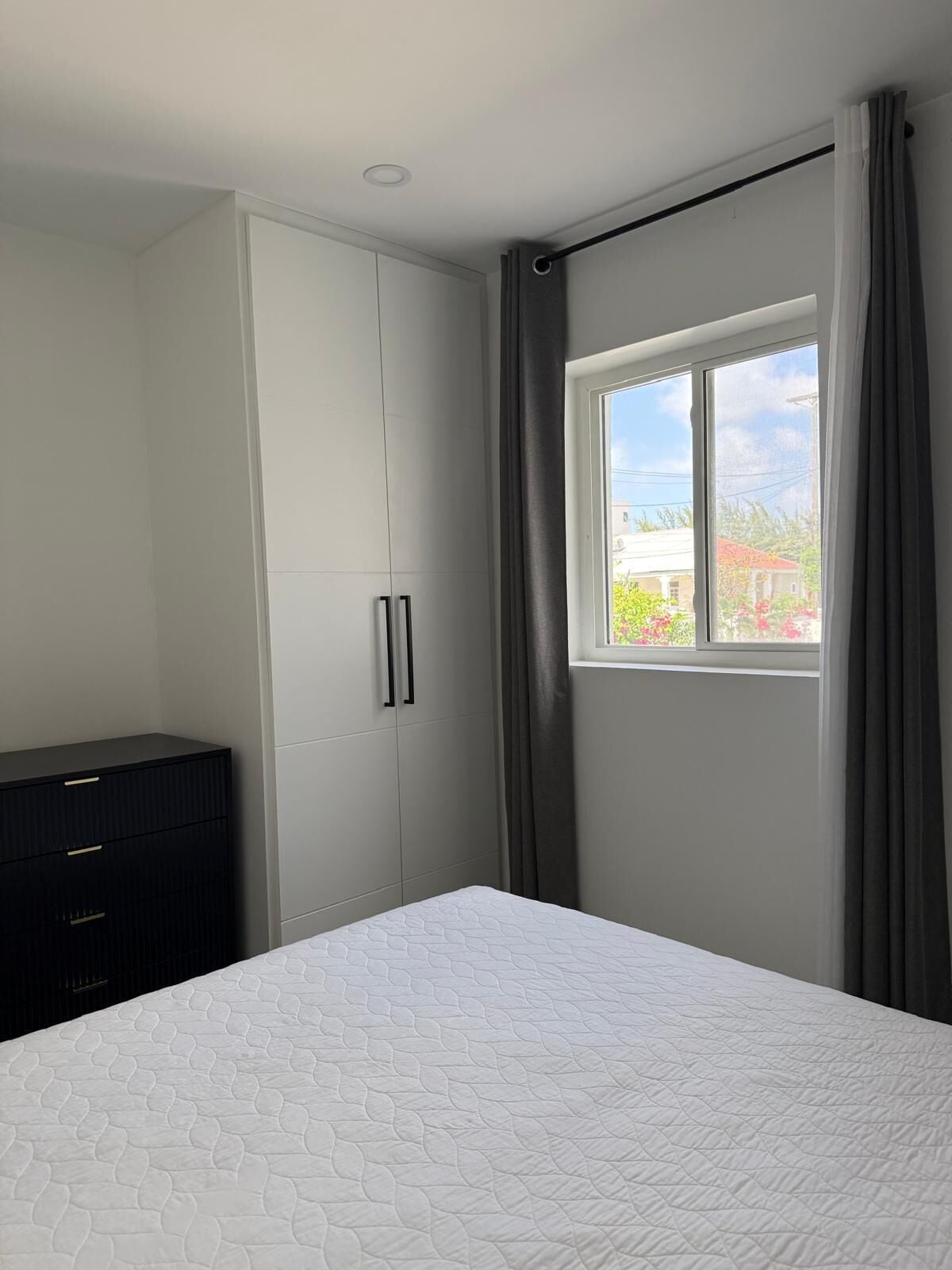 A bedroom with a bed, a wardrobe, and a window with curtains.