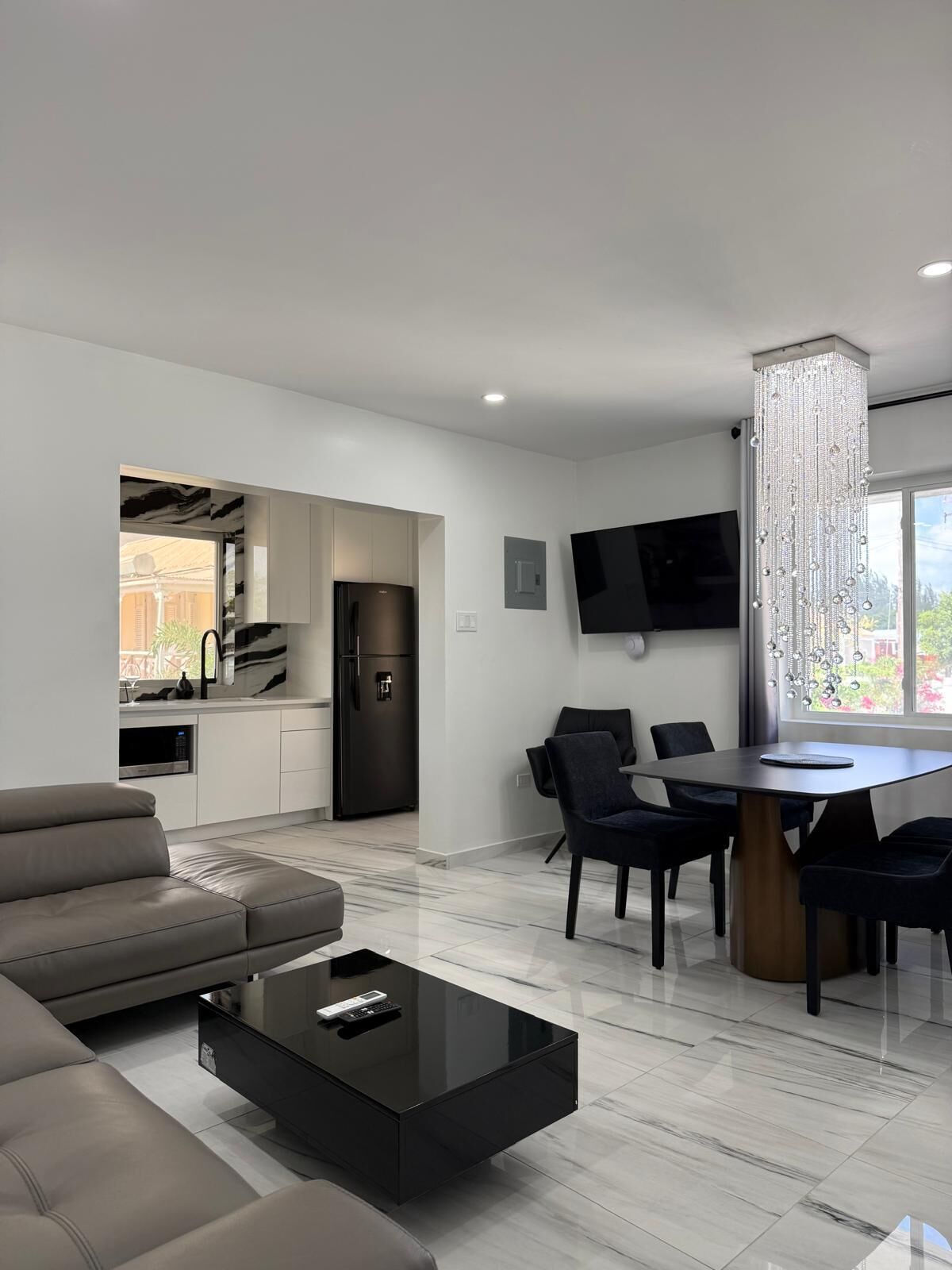 A modern living room with a sofa, a coffee table, and a dining area with chairs and a table.