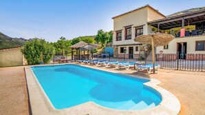 A swimming pool with lounge chairs, a building with a balcony, and a mountain backdrop. - Montion Jimera de Libar by Ruralidays (Málaga)