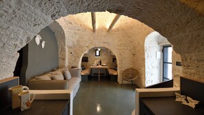 Ein gemütliches Interieur mit einem Steingewölbe, einer Couch, einem Esstisch und einem Stuhl.