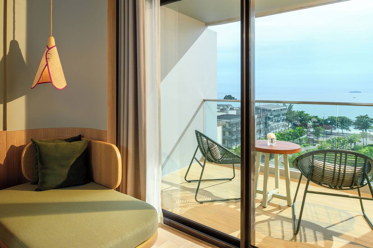 A balcony with a wooden floor, a small round table, two chairs, and a hanging light fixture.