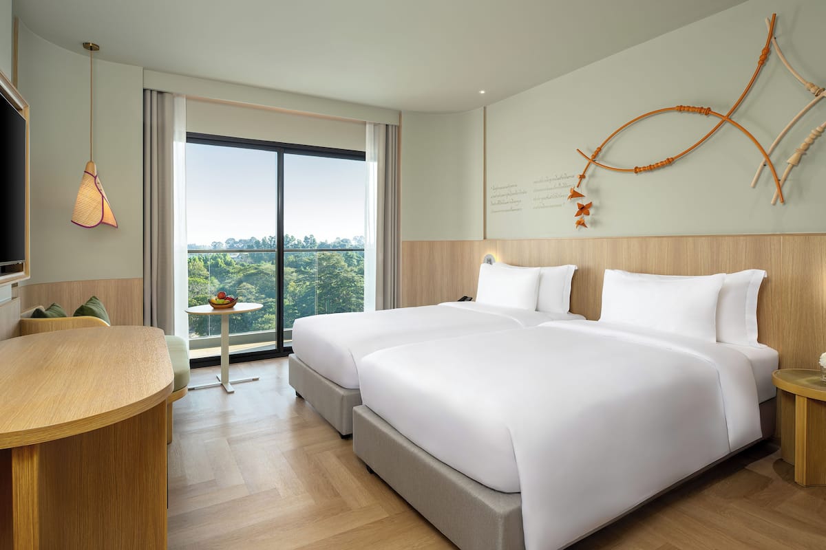 A modern hotel room with two beds, a dining area, and a large window with a view.