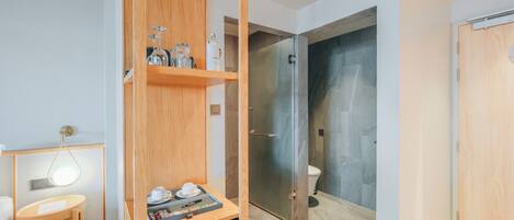 Un baño moderno con ducha, inodoro y tocador de madera con lavamanos y encimera.