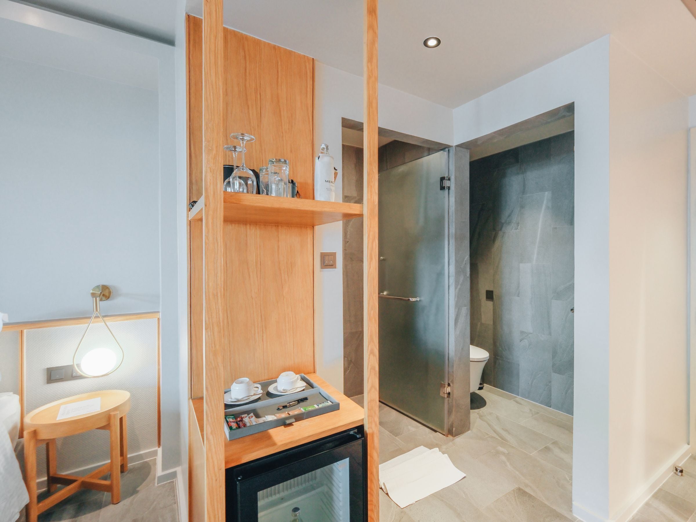 A modern bathroom with a glass shower enclosure, a wooden vanity, and a small table with a tray.