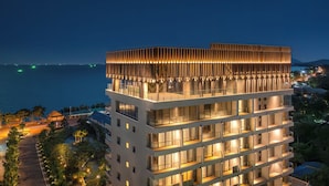 A multi-story hotel with a modern design, featuring balconies and large windows, situated near a body of water. - Mercure Rayong Lomtalay Villas & Resort (Klaeng)