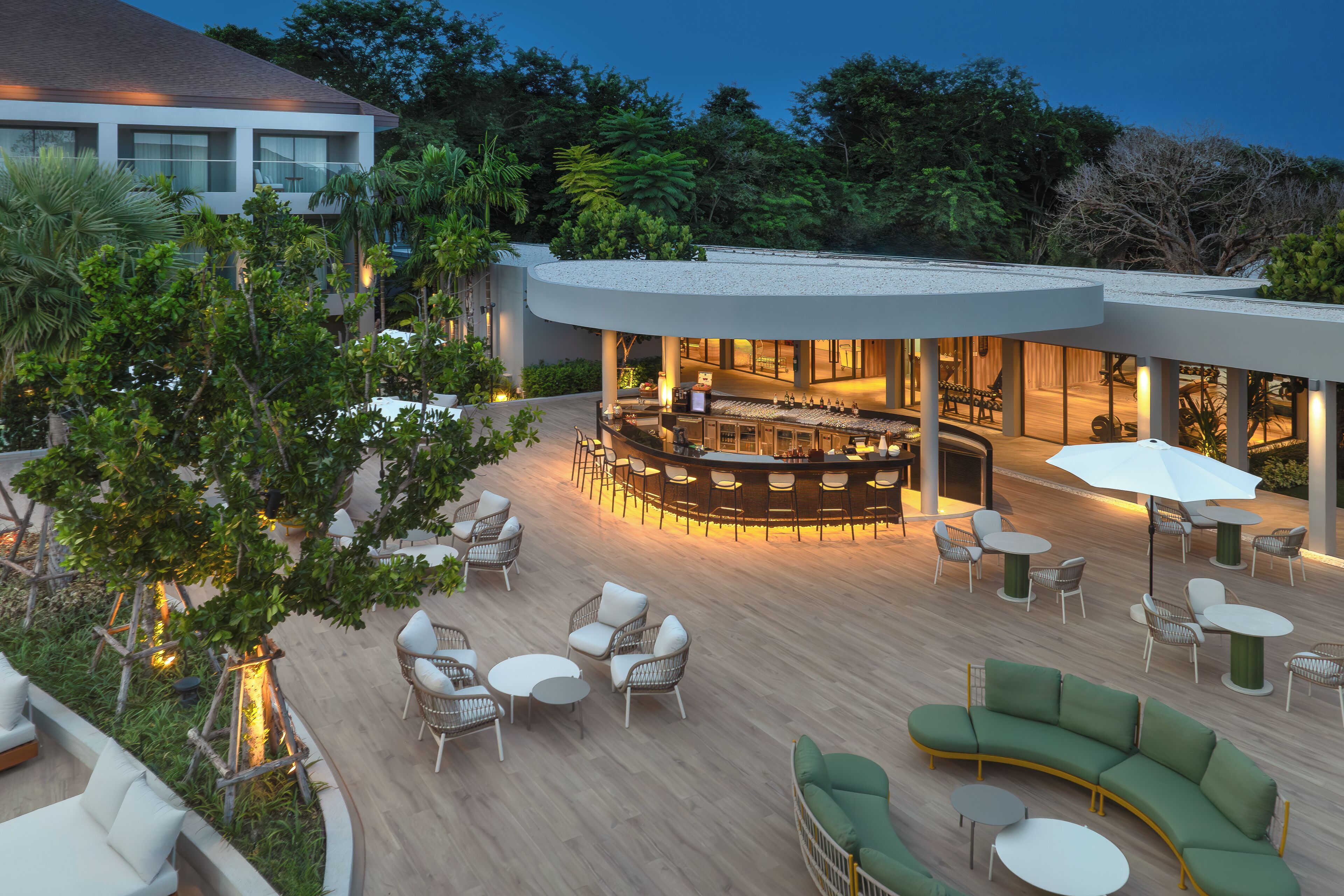 Uma área de estar moderna ao ar livre, com bar curvo, assentos e ambiente junto à piscina.