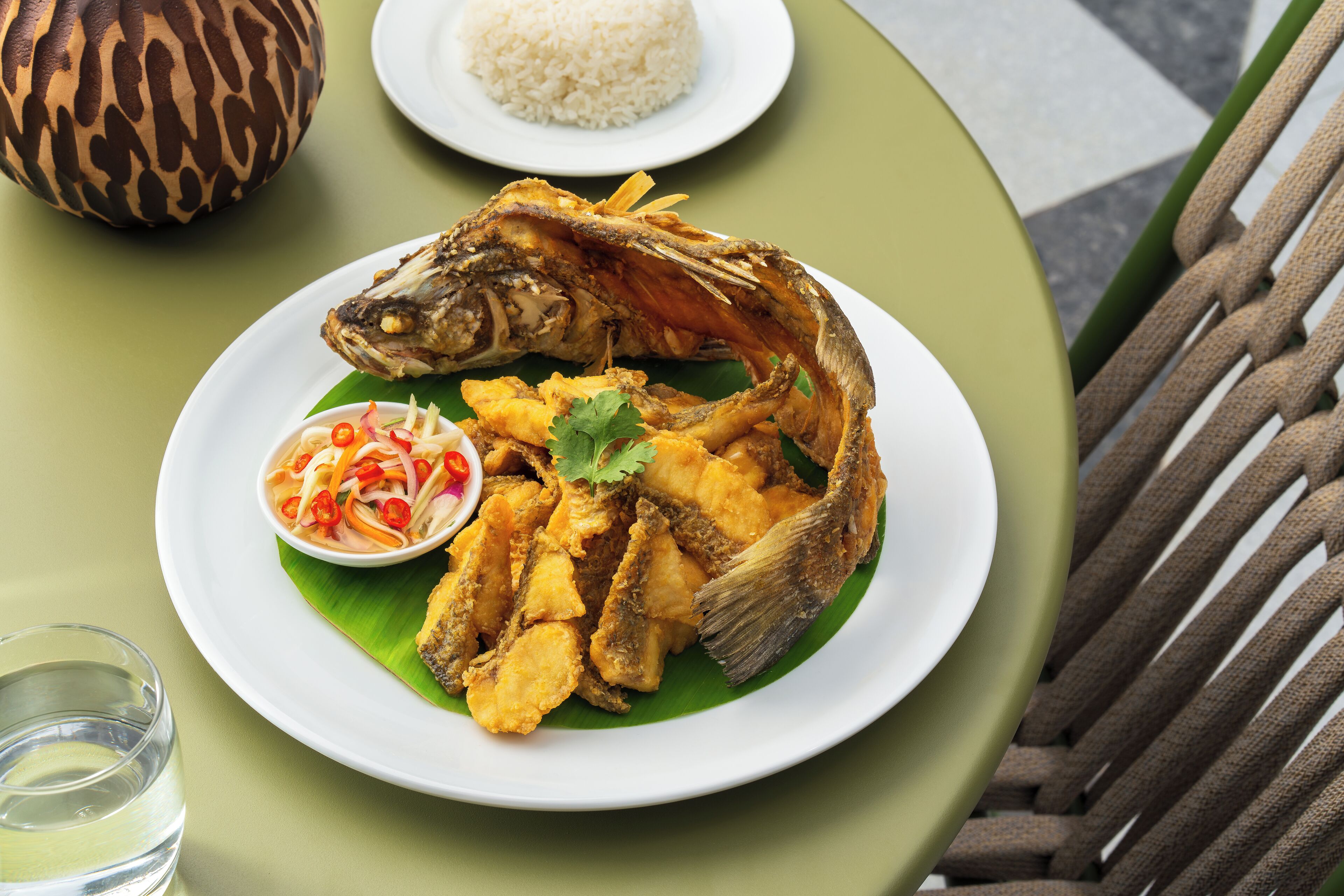 A plate of fried fish with a side of rice and a small bowl of salad.