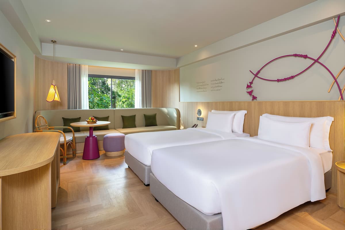 A hotel room with two beds, a sofa, a dining table, and a TV.