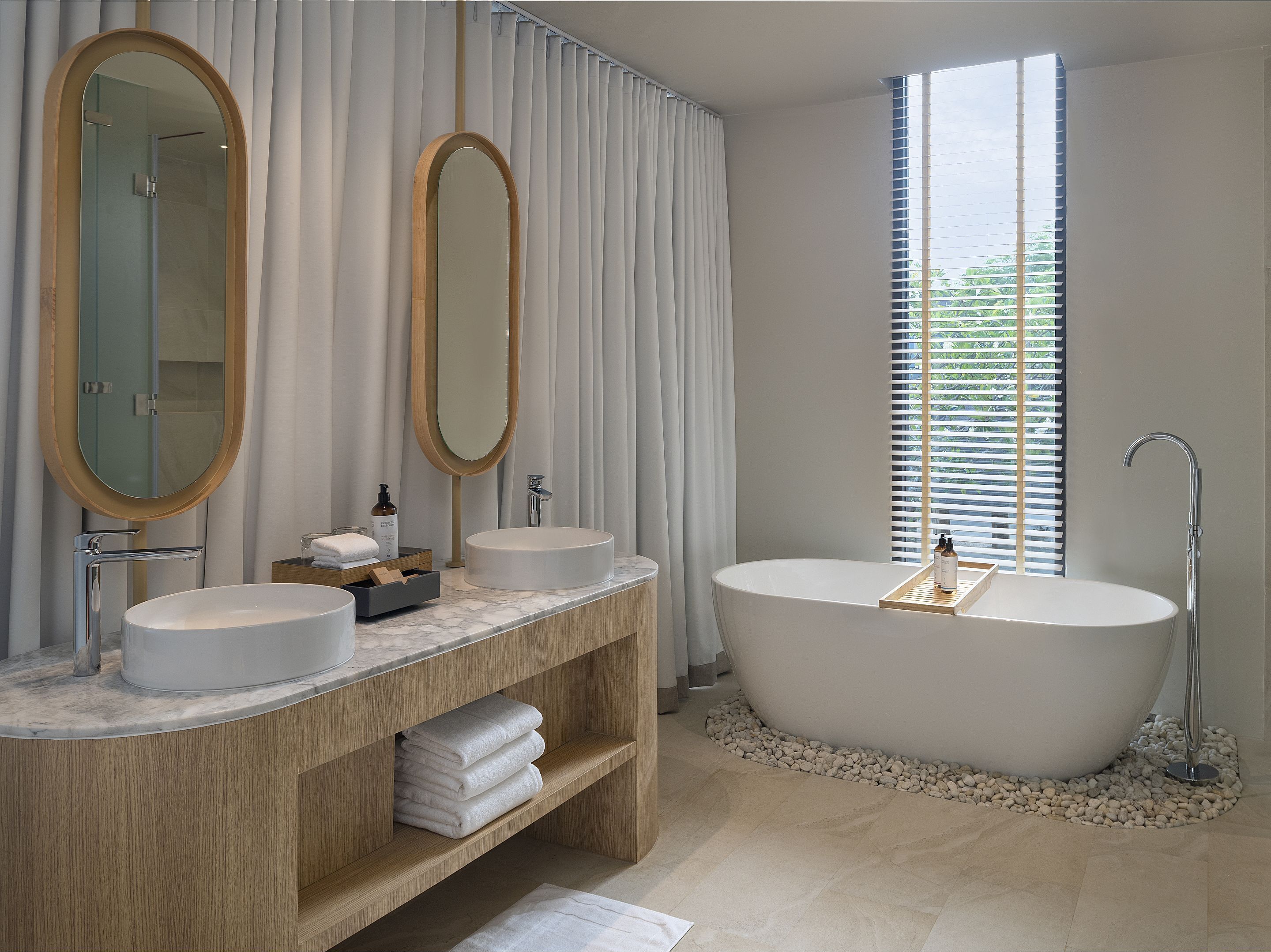 Ein modernes Badezimmer mit zwei Waschbecken, einer großzügigen, freistehenden Badewanne und einem Waschtisch mit Stauraum.