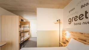 Een moderne hotelkamer met een stapelbed, een nachtkastje, een lamp en een muur met tekst.