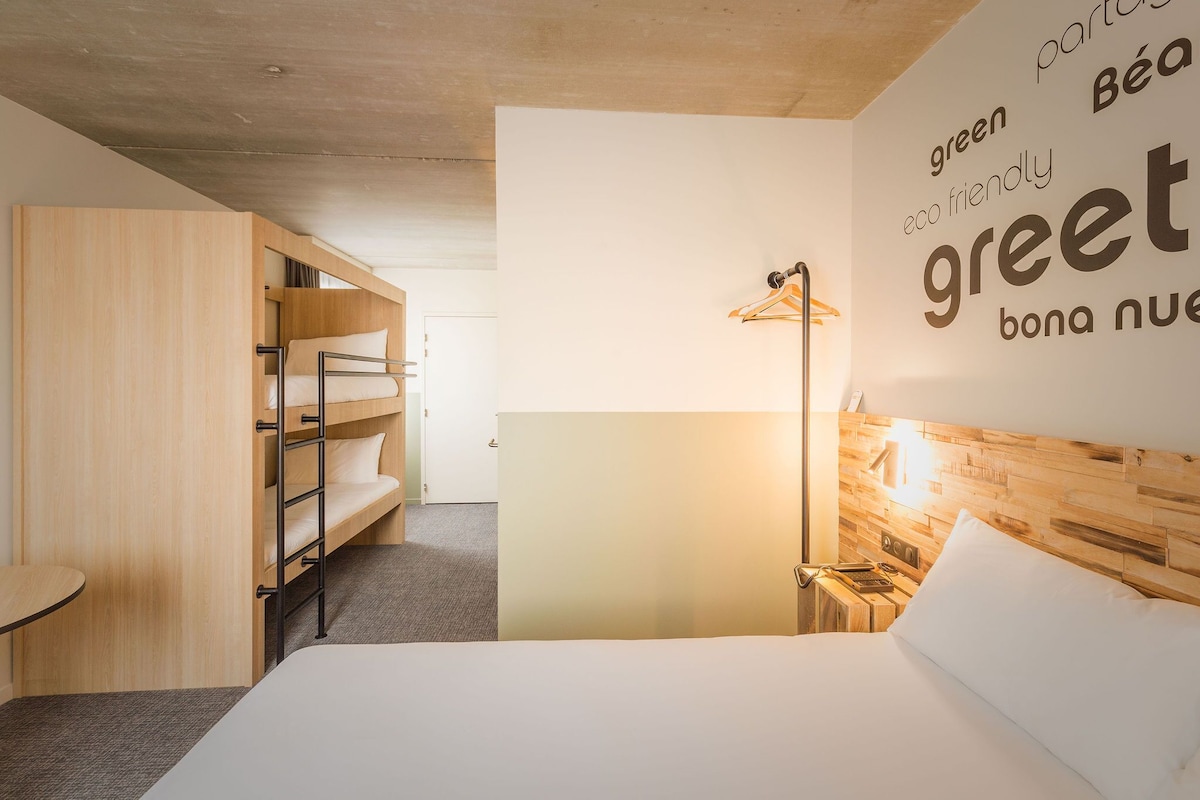 Een moderne hotelkamer met een stapelbed, een nachtkastje, een lamp en een muur met tekst.