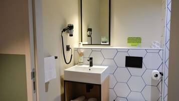 Een badkamer met een wastafel, spiegel, handdoekhouder en een wand met een honingraatpatroon.