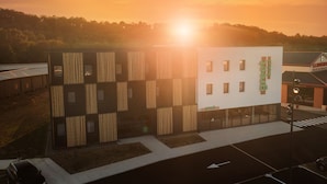 Een modern hotel met een plat dak en een grote glazen gevel.