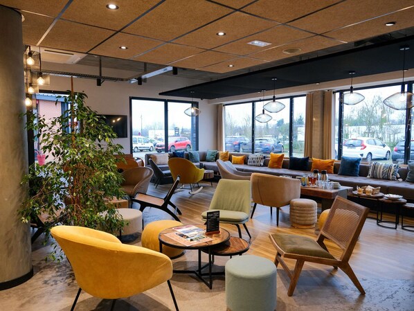 Un intérieur moderne avec un coin salon, de grandes fenêtres et une vue sur les voitures garées à l’extérieur.