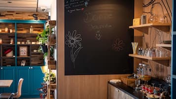 Acogedor interior de café con una pizarra de menú, estantes de madera y una zona de bar.