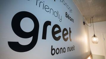 Uma parede com texto em vários idiomas, incluindo 'greet' e 'bona nuit'.