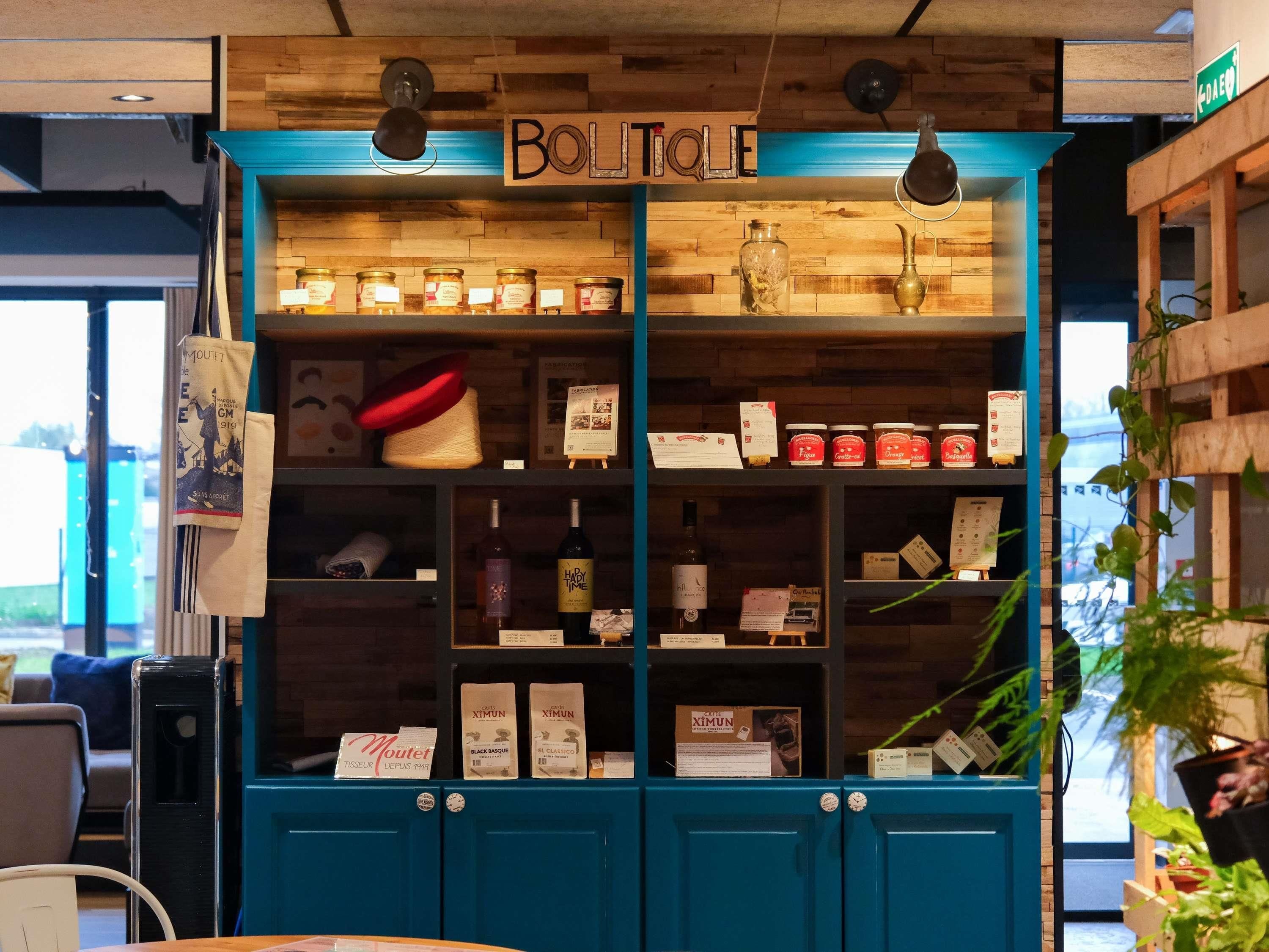 Een boetiek met houten schappen waarop diverse producten staan uitgestald, een bord met de tekst 'BOUTIQUE' en een blauwe deur.