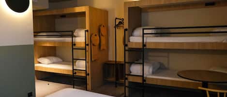 A room with bunk beds, a round table, and a small stool.