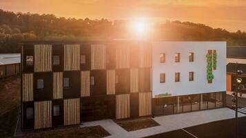 Un hotel moderno con una fachada distintiva de listones verticales de madera y un llamativo letrero que dice 'greet hotel'.
