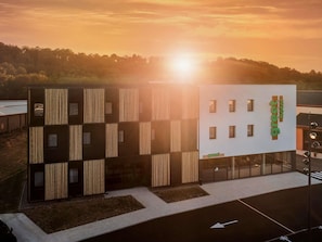 A modern hotel with a unique facade featuring vertical wooden slats and a prominent 'greet hotel' sign.