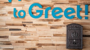 Een houten muur met de tekst 'Welcome to Greet!' en een brievenbus.