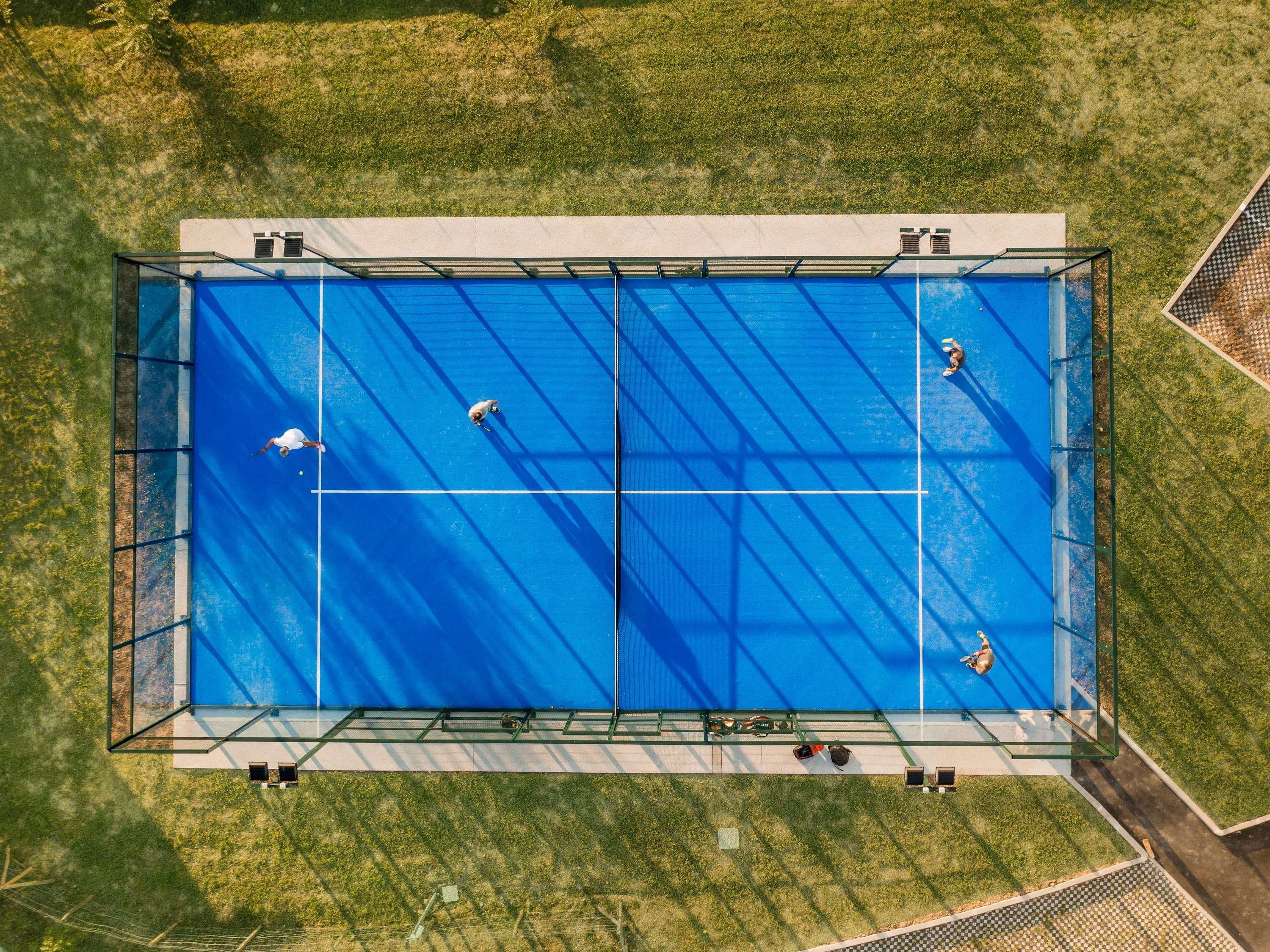 A large, rectangular swimming pool with a clear blue surface, surrounded by a metal fence and a grassy area.