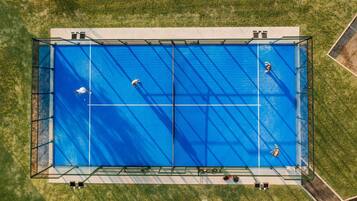 A large, rectangular swimming pool with a clear blue surface, surrounded by a metal fence and a grassy area.