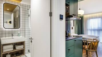 A modern bathroom with a white sink, mirror, and shelves with towels.