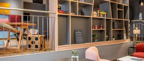 A modern interior with a round table, seating, and a bookshelf with various items.