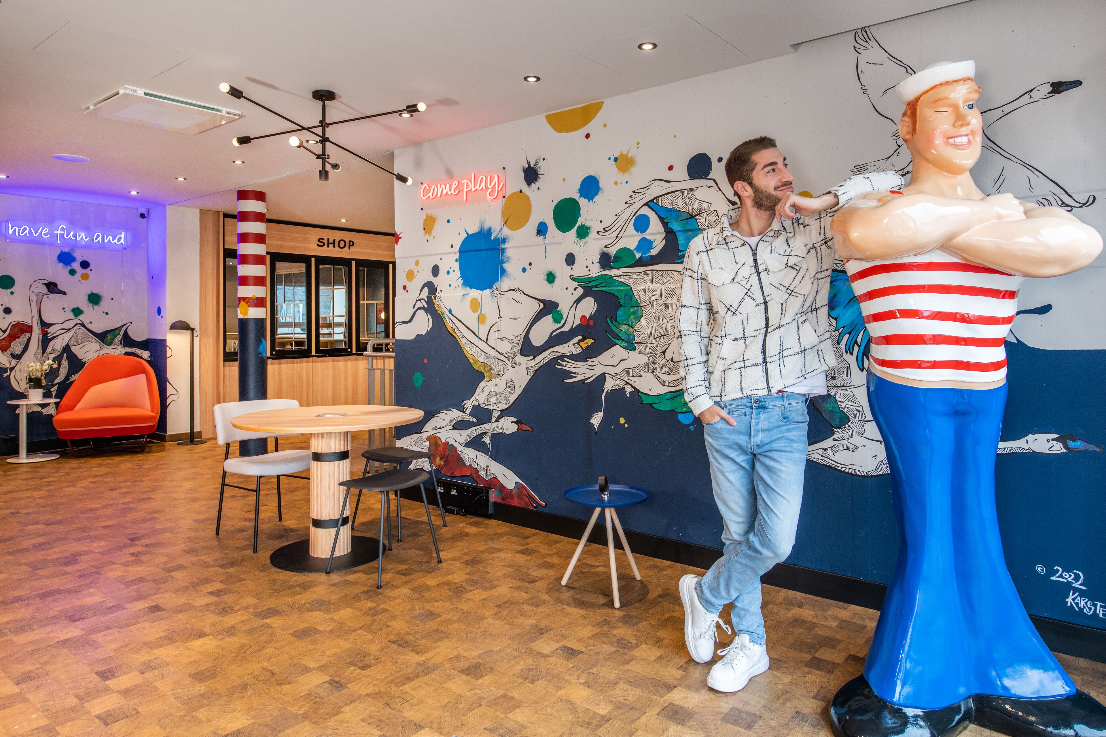 Un interior moderno con suelo de madera, una tienda y un mural colorido.