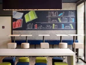 A modern library with bookshelves, seating, and tables. - ibis budget Montceau-les-Mines (Montceau-les-Mines)