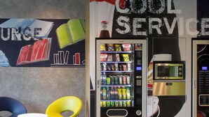 A vending machine with a microwave and a coffee machine, two chairs, and a wall with a 'Cool Service' sign. - ibis budget Montceau-les-Mines (Montceau-les-Mines)