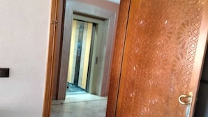 Corredor com porta de madeira e vista para outro quarto.