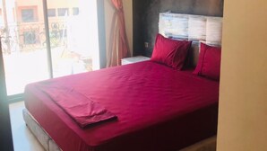 Quarto com uma cama grande, mesa de cabeceira e janela com cortinas.