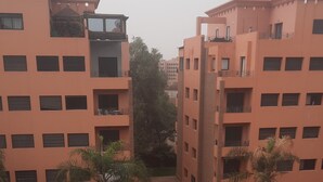 Um edifício residencial com vários andares, varandas e área de piscina com espreguiçadeiras.