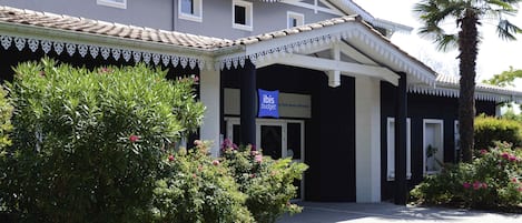 Un edificio con un letrero que dice 'ibis budget' y una entrada cubierta.