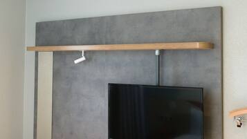 Een moderne kamer met een wandgemonteerde flatscreen televisie, houten planken en een plafondlamp.