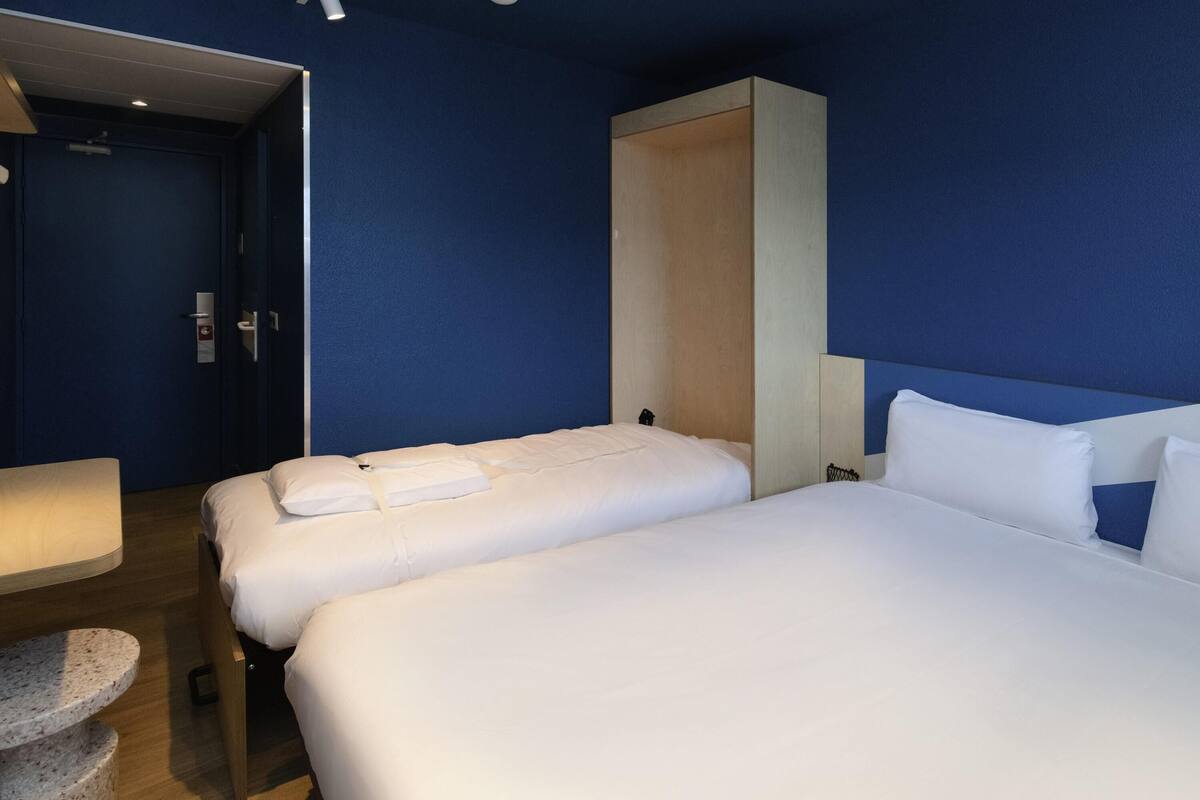 A hotel room with two beds, a desk, and a chair.