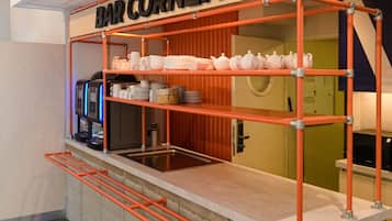 A bar area with a sign reading "BAR CORNER," equipped with a coffee machine, shelves of dishes, and a countertop.