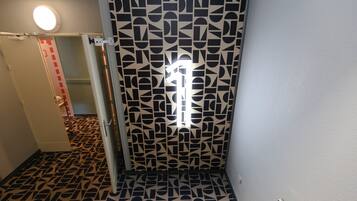A hallway with patterned floor tiles, a door with a geometric design, and a light fixture on the ceiling.