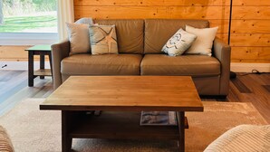 A wooden-paneled room with a brown leather sofa, a wooden coffee table, and a wall-mounted lamp. - River House Getaway (Vienna)
