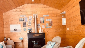 A cozy cabin interior with a fireplace, wooden walls, and various fishing-themed decorations. - River House Getaway (Vienna)