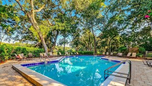 A rectangular swimming pool with a blue tiled edge, surrounded by lounge chairs and a brick patio. - Newly remodeled! Upscale Condo on the World-renowned Amelia Island Plantation! (Fernandina Beach)