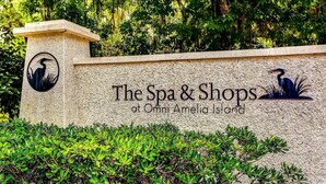 A sign for "The Spa & Shops at Omni Amelia Island" with a logo of a bird and greenery. - Newly remodeled! Upscale Condo on the World-renowned Amelia Island Plantation! (Fernandina Beach)