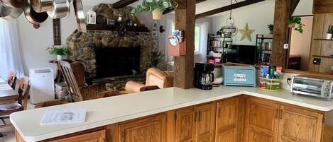 Una cucina con mobili in legno, un camino in pietra, pentole appese e una macchina per il caffè.