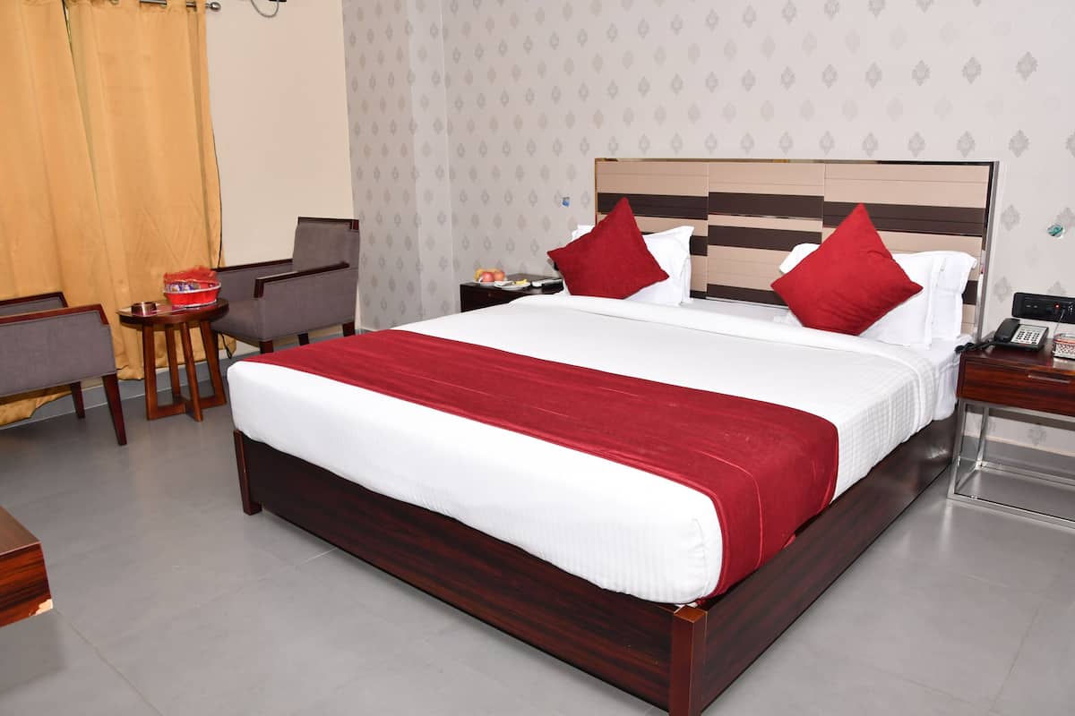 A hotel room with a large bed, two nightstands, a small table, and a chair.