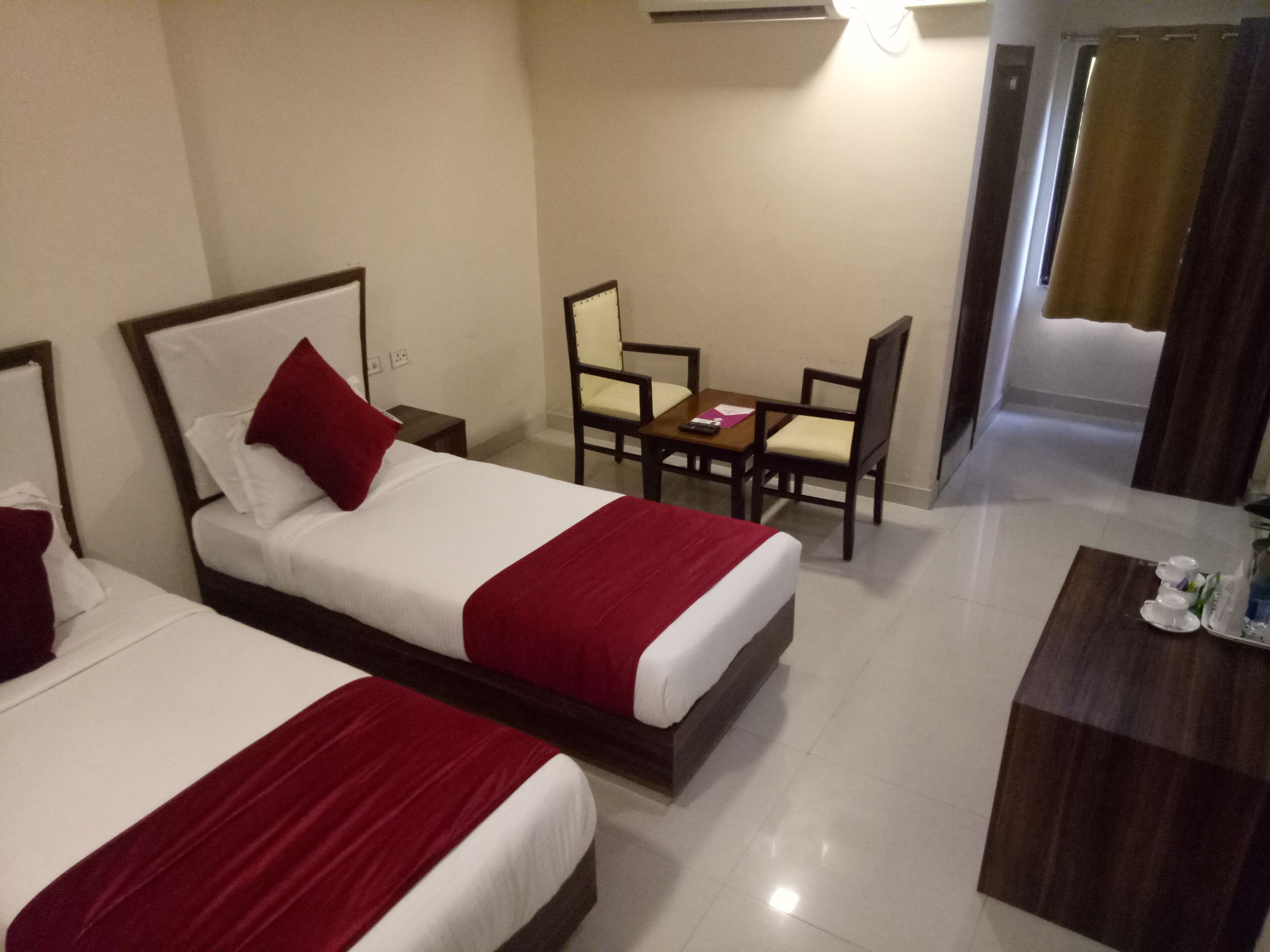 A hotel room with two beds, a small table, and a chair.