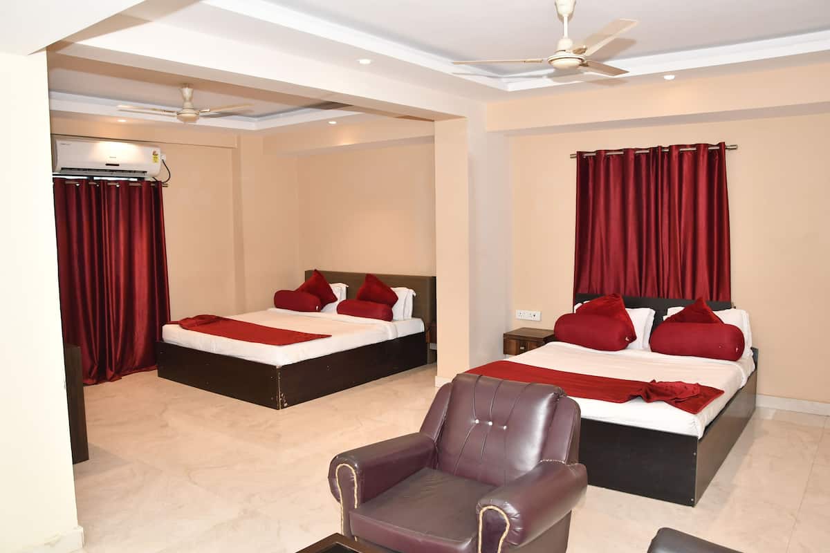 A hotel room with two beds, red curtains, a ceiling fan, and a leather armchair.