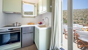 Eine kleine Küche mit Einbauofen, Kühlschrank und Fenster mit Blick auf eine felsige Landschaft.