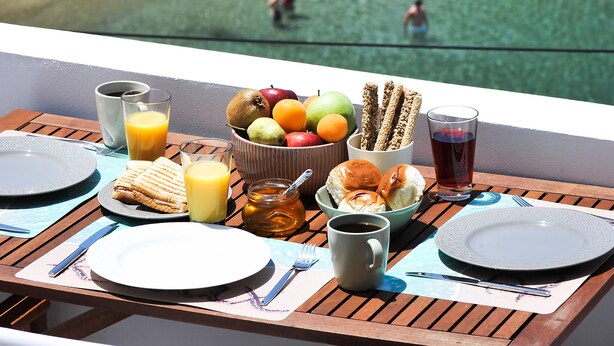 Ein Tisch mit Frühstücksgebäck und Blick auf weiße Häuser am Meer.
